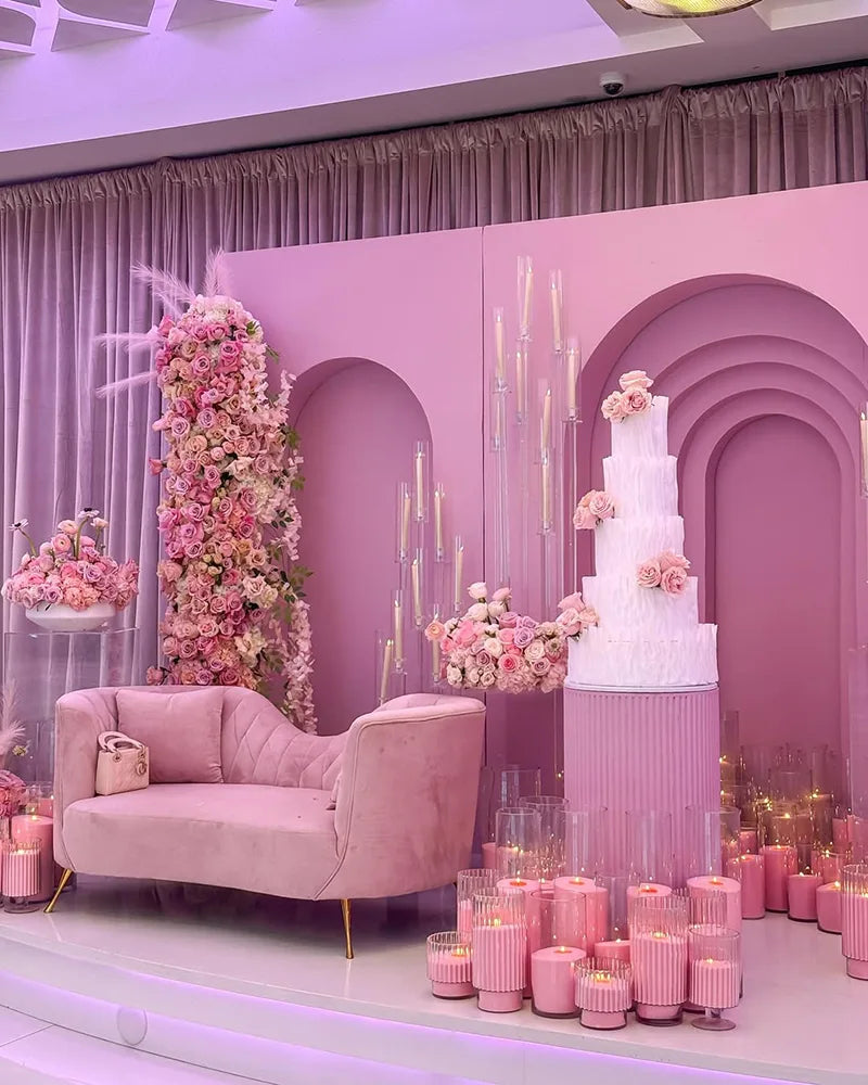 Pink celebration stage with a tiered cake and floral backdrop at Avana Venue