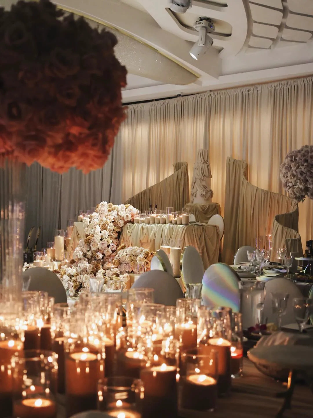 Candlelit ballroom with white and blush flowers and golden drapery at Avana Venue